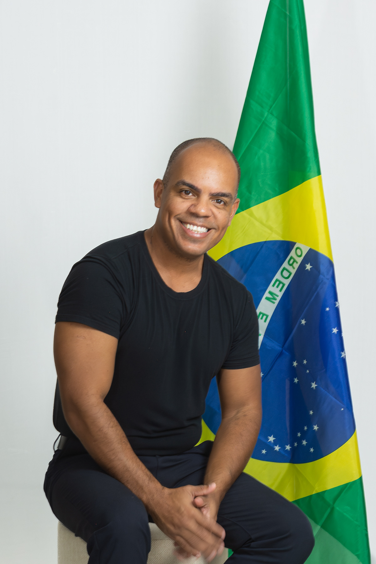 Roberto de camiseta preta ao lado da bandeira do Brasil