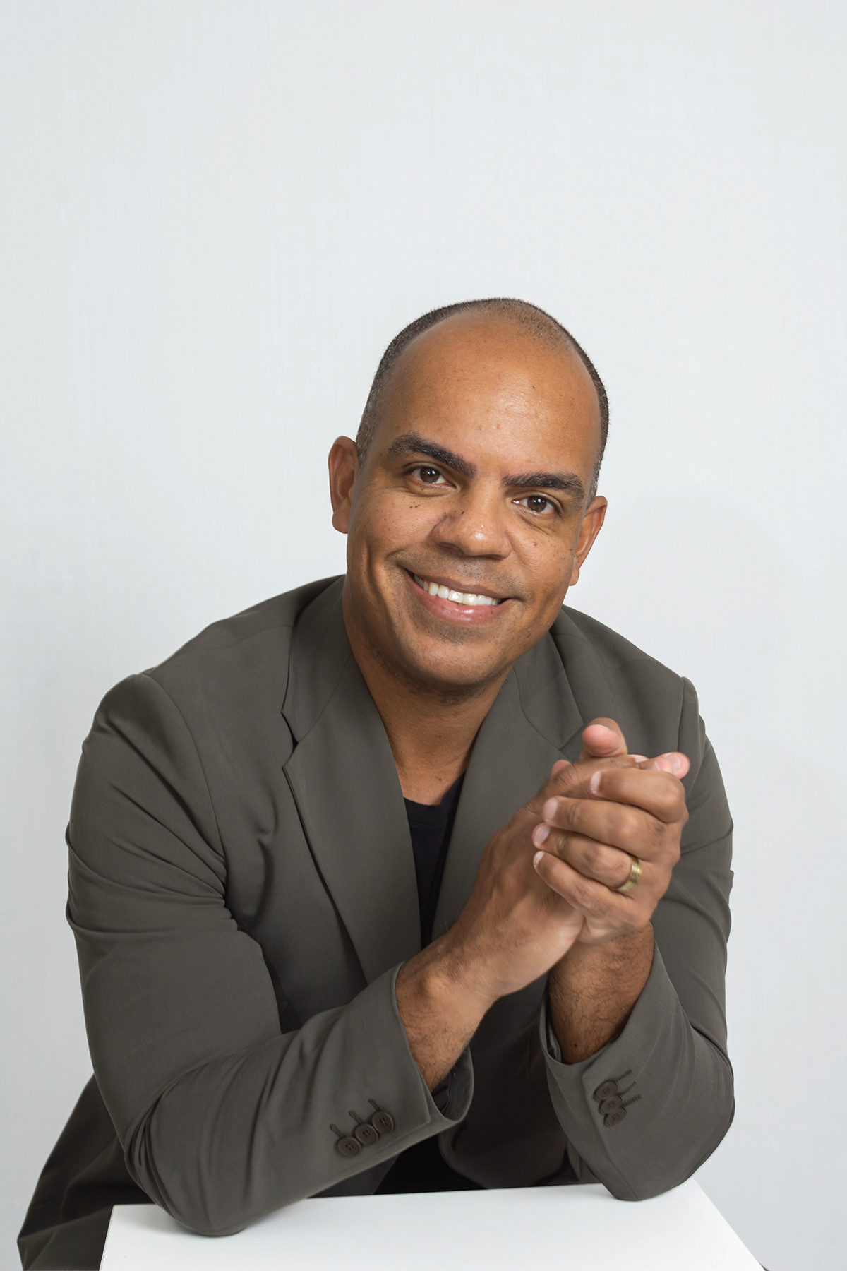 Roberto sentado, mão no queixo, blazer cinza