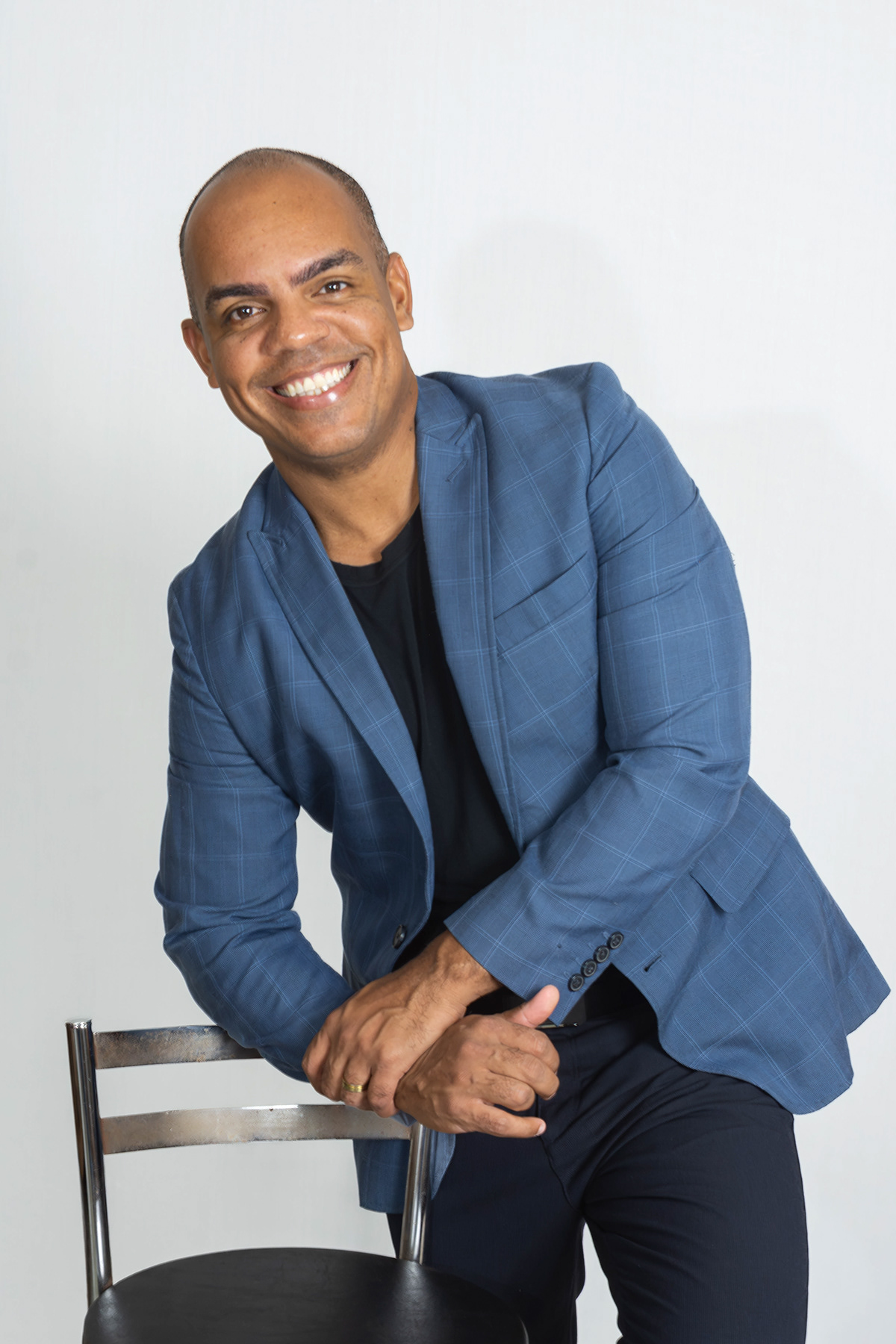 Roberto sentado em banqueta, blazer azul